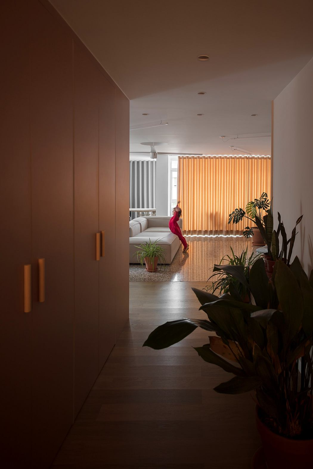 襄樊市现代简约白领公寓室内设计案例,粉色开放式厨房、粉色桌子、阳光餐厅、客厅工作间、,白色墙原木护墙板、客厅风扇、龟背竹盆栽、水磨石地板